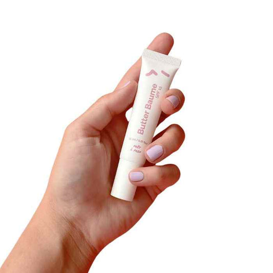 Hand holding a tube of Prêt à Prep Butter Baume Lip Butter for deep lip hydration and nourishment