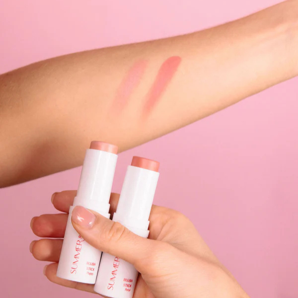 Two Summer & Lu Blush Sticks in peachy shades with matching swatches on arm against pink background